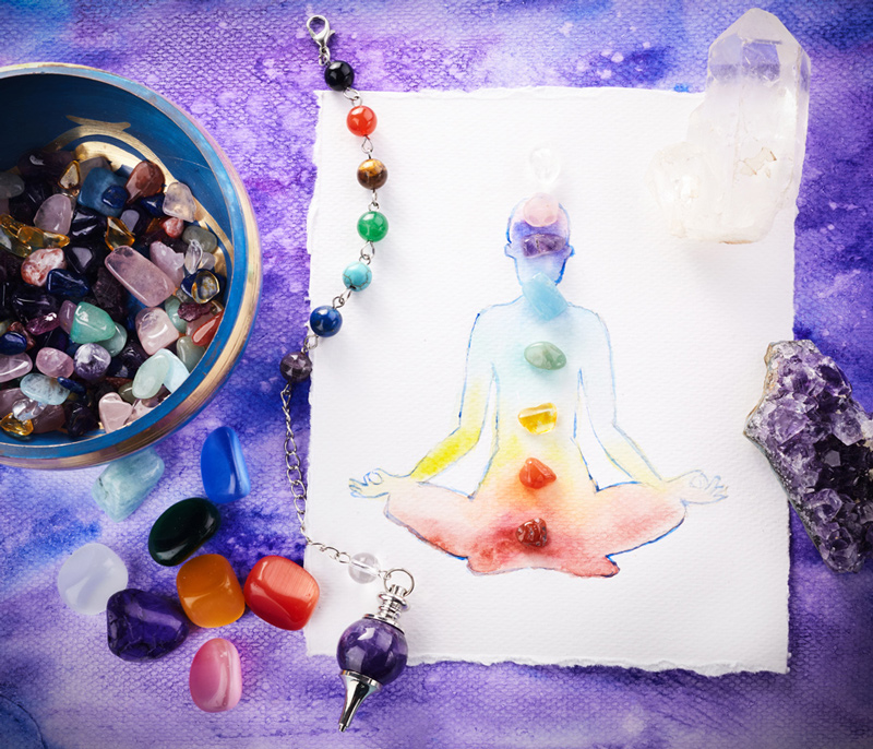 An array of chakra colored gemstones, a picture of a person with the 7 chakra colors over their body.